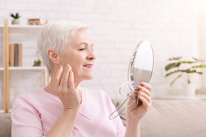 Older woman looking at her face in a mirror