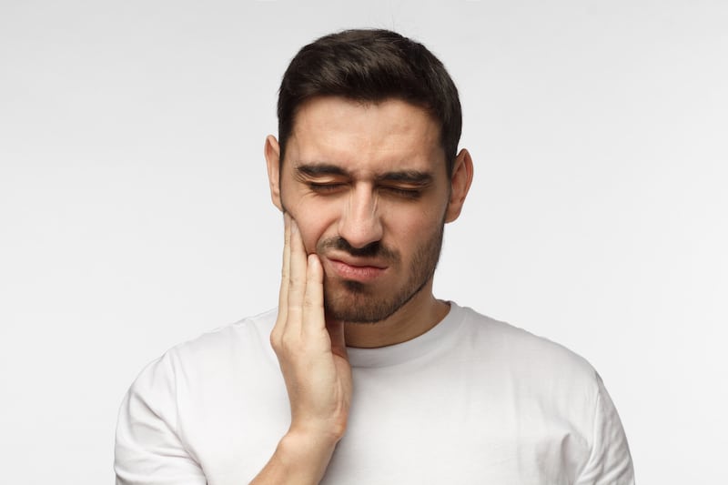 Man holding his cheek with his hand feeling jaw pain