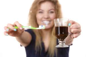 Woman holds a dark drink and a toothbrush in Oakton, VA