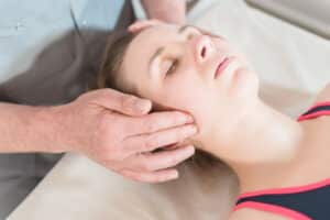 Man massages woman’s face to relieve tension and pain in her jaw. Physical therapy can help with TMJ