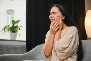 A woman with a root canal holding her jaw