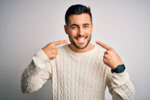 A man with dental implants pointing to his teeth