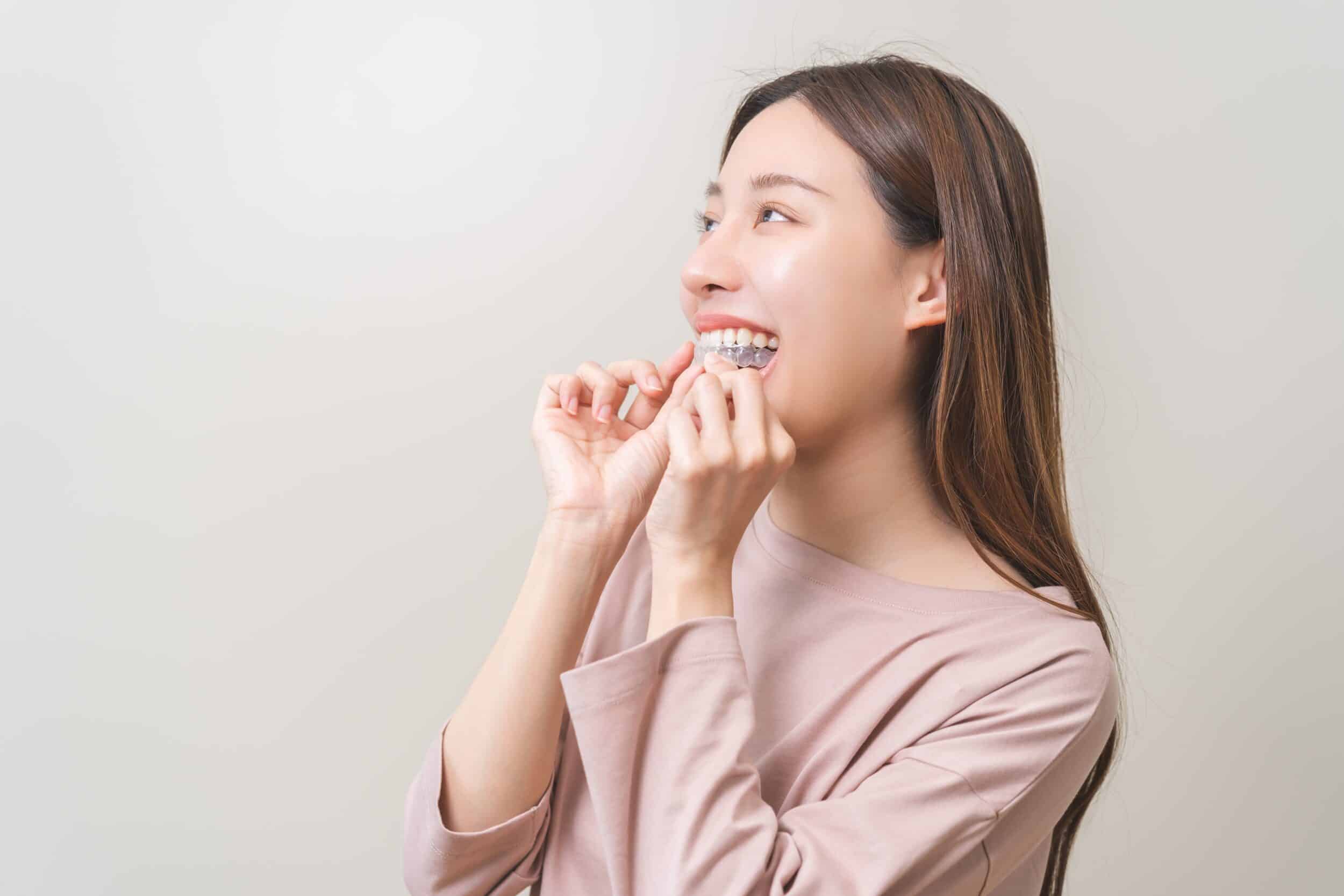 A woman removing Invisalign aligners