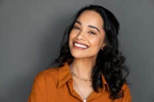 Beautiful woman wearing orange flashes a big smile with white teeth.