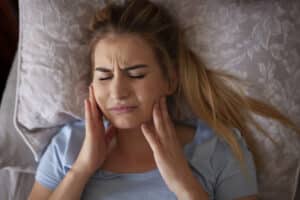Woman experiencing TMJ jaw discomfort.