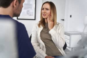 Woman discussing tooth pain with dentist.